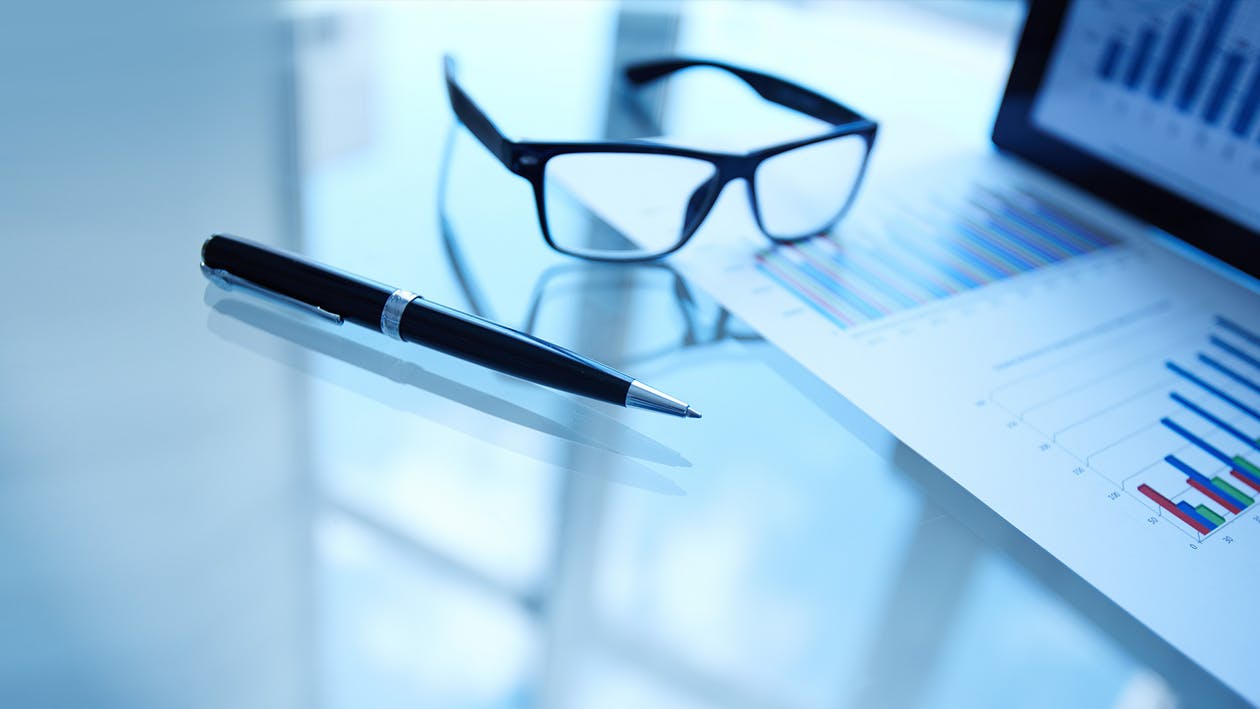 Eyeglases and a pen at a desk.